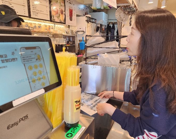 화산동 관계자가 카페를 방문해 종이팩 별도 수거 사업을 홍보하며 전용 수거 봉투를 전달하고 있다